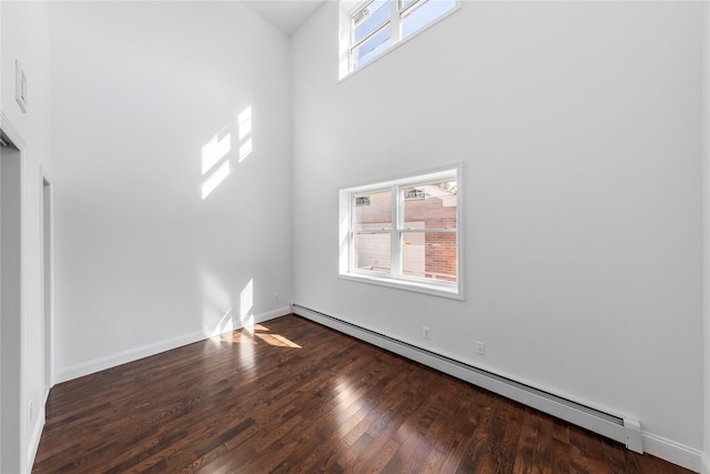 interior space with a high ceiling, hardwood / wood-style flooring, and a baseboard heating unit