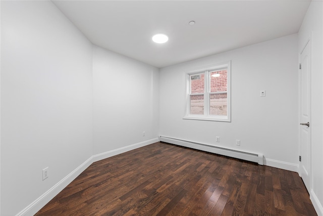 empty room with dark hardwood / wood-style flooring and a baseboard radiator