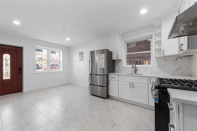 kitchen with appliances with stainless steel finishes, sink, white cabinetry, and range hood