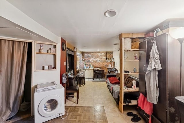 clothes washing area featuring light parquet flooring, brick wall, and washer / dryer