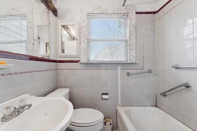 bathroom with a wealth of natural light, toilet, tile walls, and sink