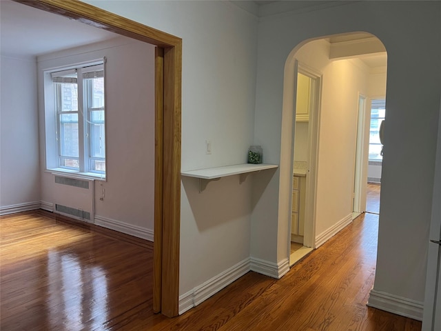 corridor with radiator, crown molding, and hardwood / wood-style flooring