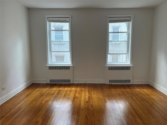 spare room featuring radiator and wood-type flooring