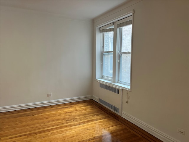 unfurnished room with light hardwood / wood-style floors and radiator heating unit