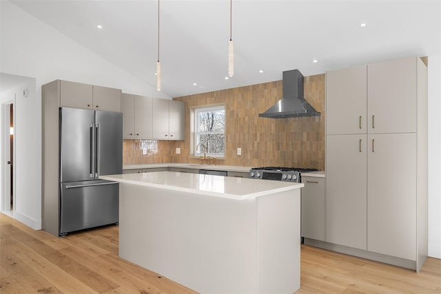 kitchen featuring a center island, hanging light fixtures, stainless steel appliances, wall chimney range hood, and backsplash