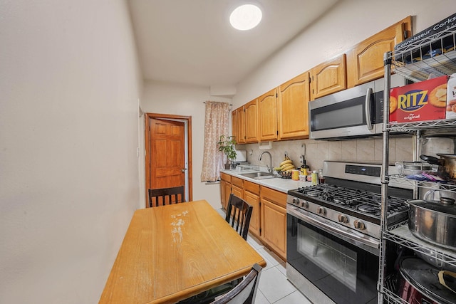 kitchen with tasteful backsplash, sink, light tile patterned floors, and appliances with stainless steel finishes