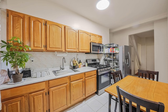 kitchen with light tile patterned flooring, appliances with stainless steel finishes, decorative backsplash, and sink