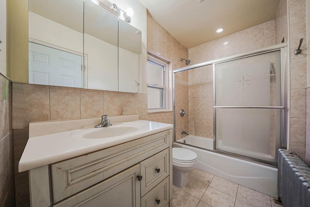 full bathroom featuring tasteful backsplash, bath / shower combo with glass door, vanity, radiator heating unit, and toilet