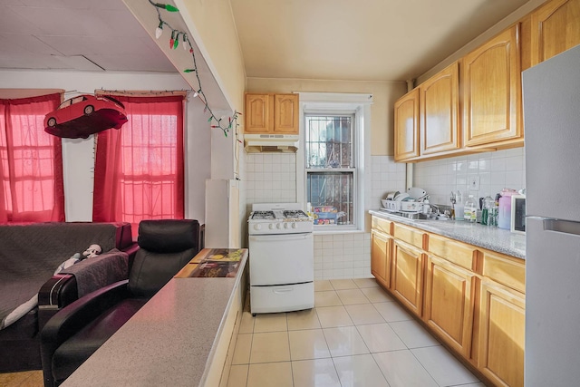 kitchen with backsplash, light brown cabinetry, light tile patterned floors, and white appliances