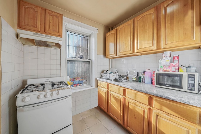 kitchen featuring light tile patterned flooring, sink, light stone countertops, and white gas range oven