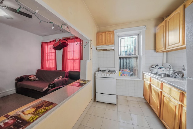 kitchen featuring light brown cabinets, sink, rail lighting, light tile patterned floors, and gas range gas stove