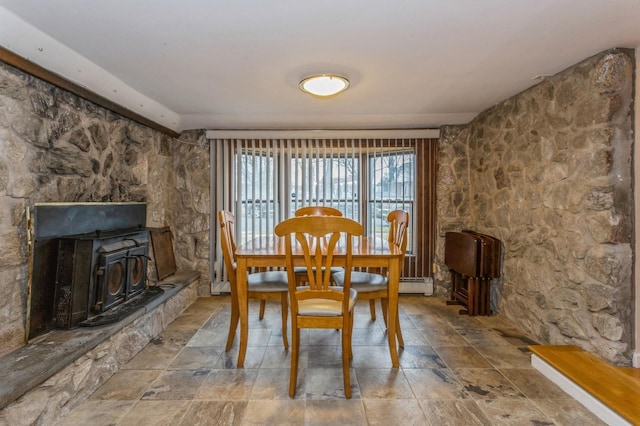 dining area featuring baseboard heating and a wood stove