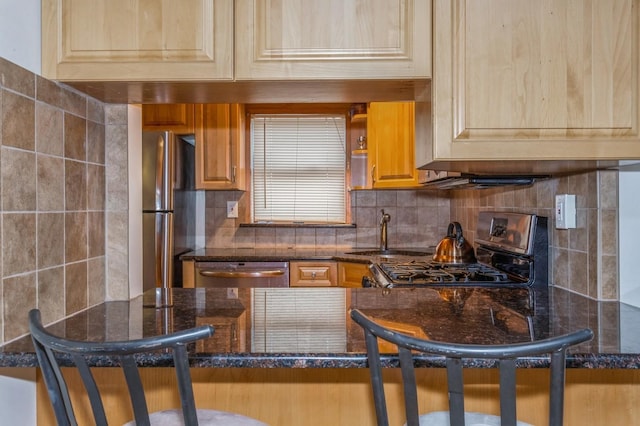 kitchen with stainless steel appliances, sink, backsplash, and dark stone counters