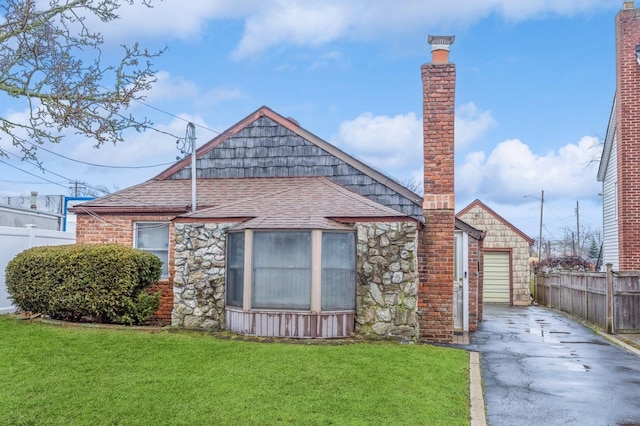 rear view of house featuring an outbuilding, a garage, and a lawn