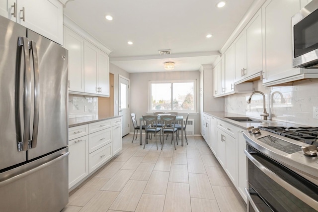 kitchen featuring light stone countertops, tasteful backsplash, stainless steel appliances, sink, and white cabinets