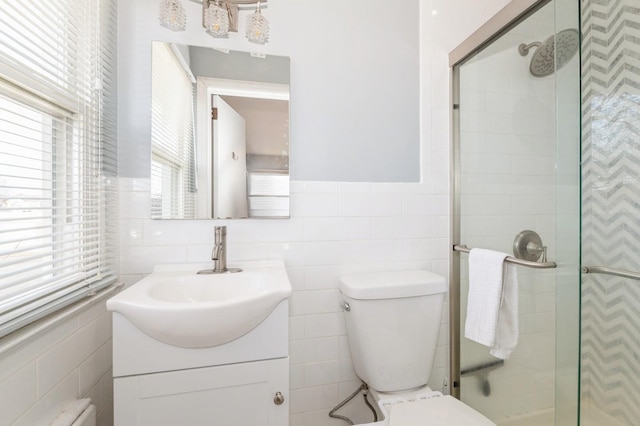 bathroom featuring a shower with door, toilet, and a wealth of natural light