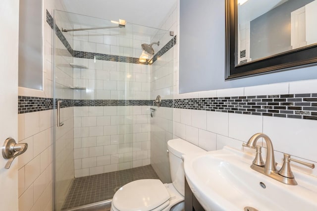 bathroom featuring toilet, a shower with shower door, sink, and tile walls