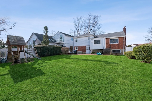 rear view of house featuring a playground and a yard