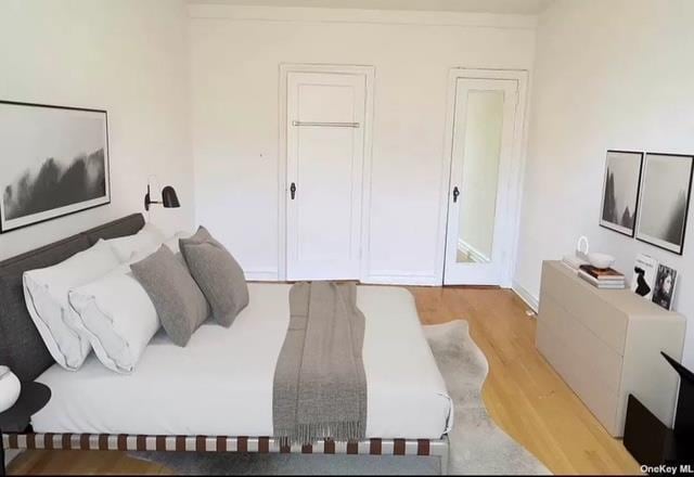 bedroom with light wood-type flooring and crown molding