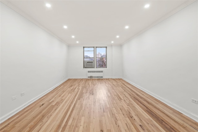 spare room featuring light hardwood / wood-style flooring, crown molding, and radiator heating unit