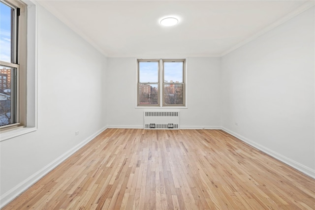 empty room featuring radiator heating unit and light hardwood / wood-style flooring