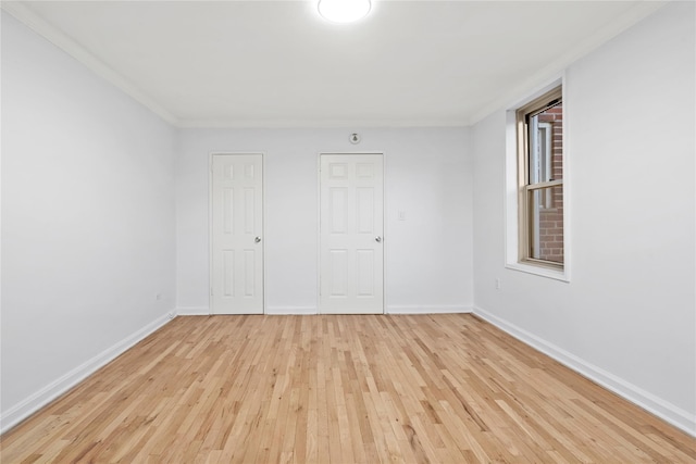 unfurnished bedroom with crown molding and light wood-type flooring