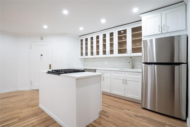 kitchen featuring sink, light wood-type flooring, stainless steel refrigerator, gas cooktop, and white cabinets