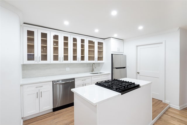 kitchen featuring stainless steel appliances, a center island, sink, and white cabinets