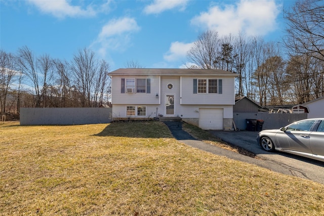 split foyer home featuring driveway, a front lawn, a garage, and fence