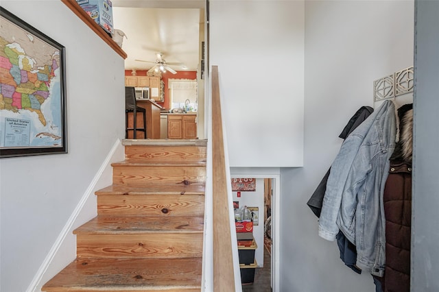 stairway with baseboards and ceiling fan