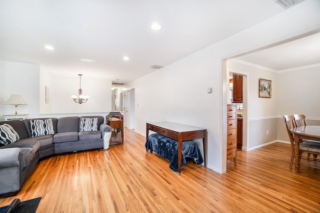 living room with light wood-type flooring, an inviting chandelier, and ornamental molding