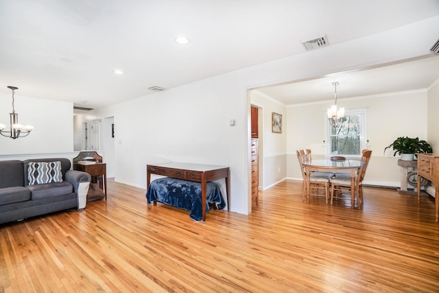 living room featuring a chandelier, light hardwood / wood-style flooring, and crown molding