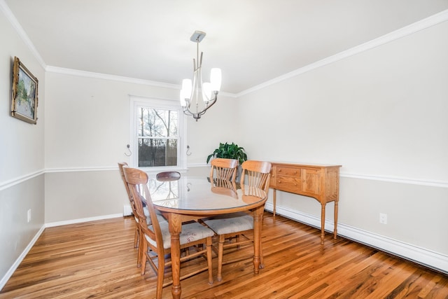 dining space featuring hardwood / wood-style flooring, ornamental molding, and an inviting chandelier