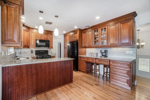 kitchen featuring pendant lighting, backsplash, black appliances, sink, and kitchen peninsula