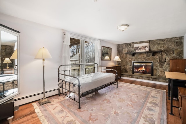 sitting room with a baseboard radiator, a stone fireplace, and hardwood / wood-style flooring