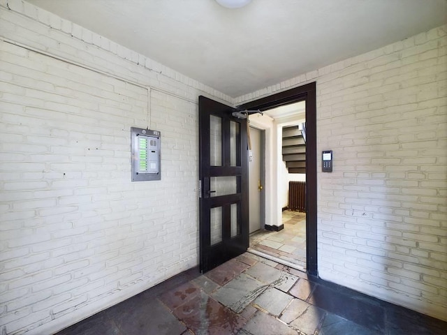 foyer featuring electric panel and brick wall