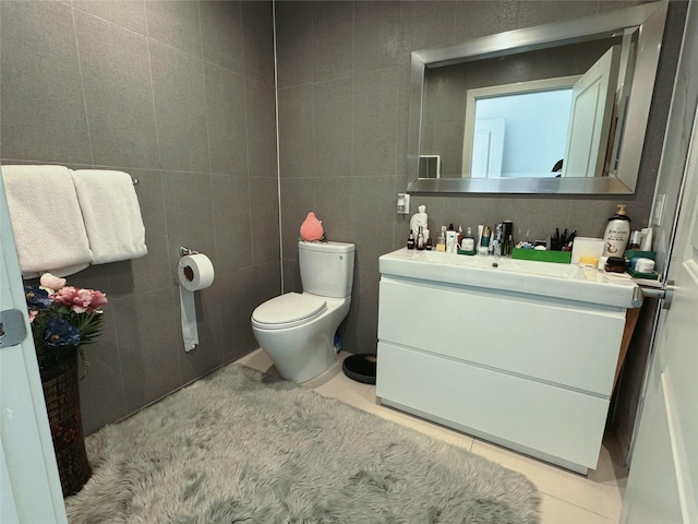 bathroom with tile patterned flooring, vanity, toilet, and tile walls