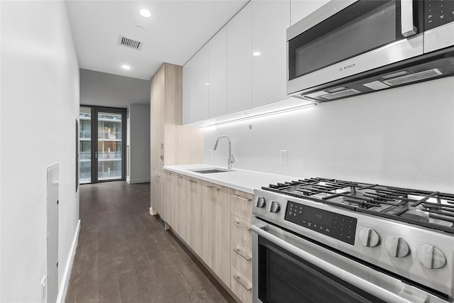 kitchen featuring light brown cabinets, white cabinets, sink, dark hardwood / wood-style floors, and appliances with stainless steel finishes