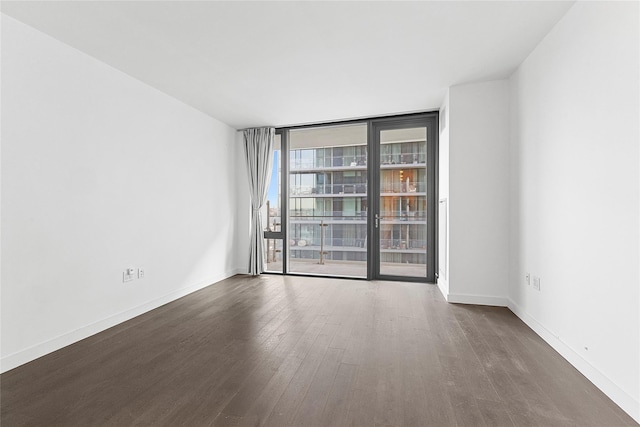 spare room featuring dark wood-type flooring and a wall of windows