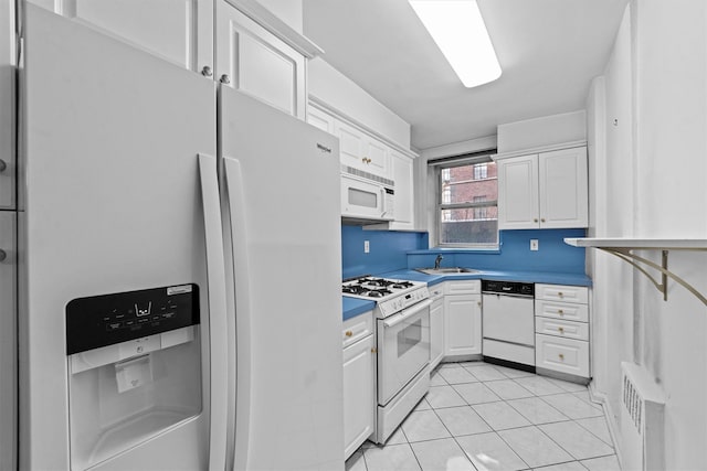 kitchen with dark countertops, white appliances, white cabinetry, and a sink