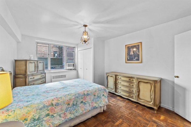 bedroom featuring a chandelier, radiator heating unit, and a closet