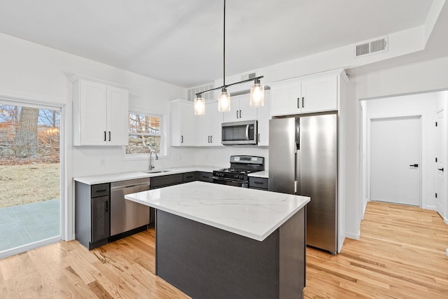 kitchen with pendant lighting, a center island, white cabinets, sink, and stainless steel appliances