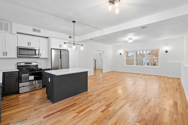 kitchen with pendant lighting, a center island, stainless steel appliances, and white cabinetry