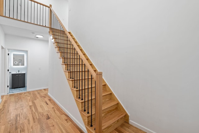 stairs with hardwood / wood-style floors and a high ceiling