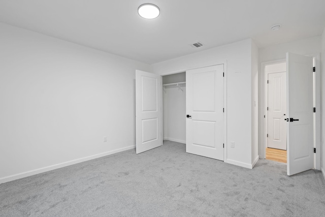 unfurnished bedroom featuring light carpet and a closet