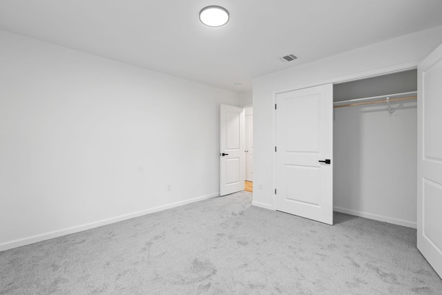 unfurnished bedroom with light colored carpet and a closet