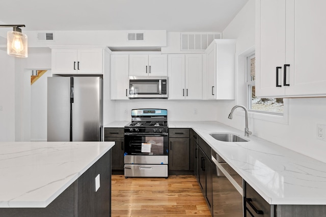 kitchen featuring white cabinets, decorative light fixtures, sink, and stainless steel appliances