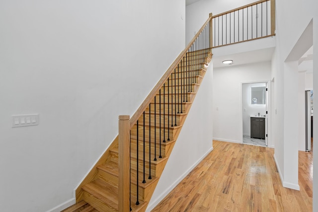 staircase with a high ceiling and hardwood / wood-style flooring