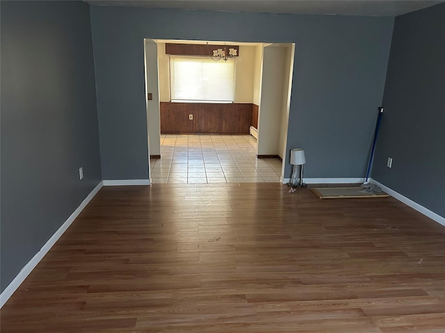 spare room with a baseboard heating unit, an inviting chandelier, and light wood-type flooring