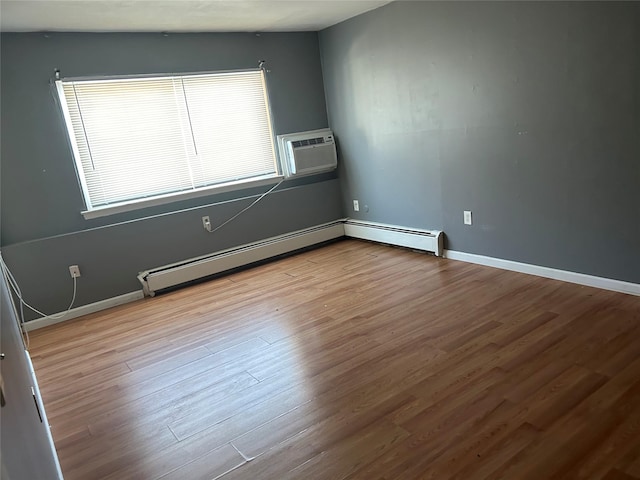 spare room with a wall mounted air conditioner, light hardwood / wood-style flooring, and baseboard heating